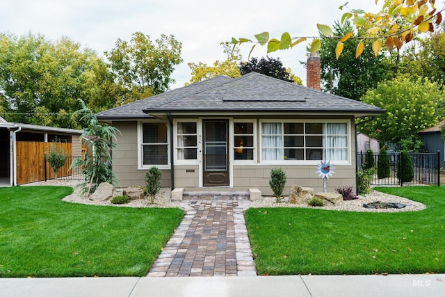 bungalow featuring a shingled roof, a front yard, fence, and a chimney