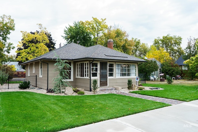 view of front of home with a front lawn, roof with shingles, a chimney, and fence