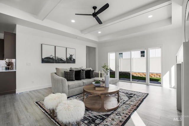 living room with beamed ceiling, light hardwood / wood-style floors, and ceiling fan