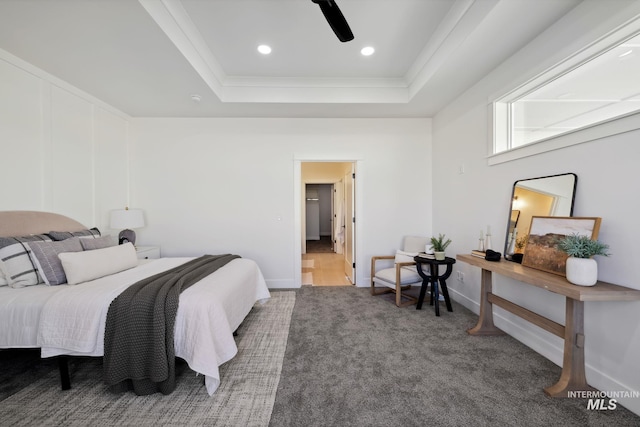carpeted bedroom with ornamental molding, baseboards, a tray ceiling, and ceiling fan
