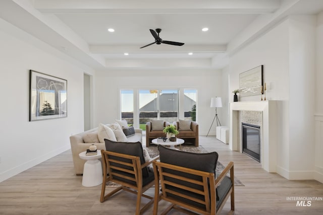 living room featuring beam ceiling, a glass covered fireplace, recessed lighting, light wood-style floors, and ceiling fan