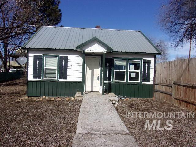 bungalow with metal roof, board and batten siding, and fence