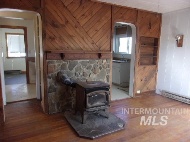 interior space with arched walkways, wood walls, wood finished floors, and a wood stove