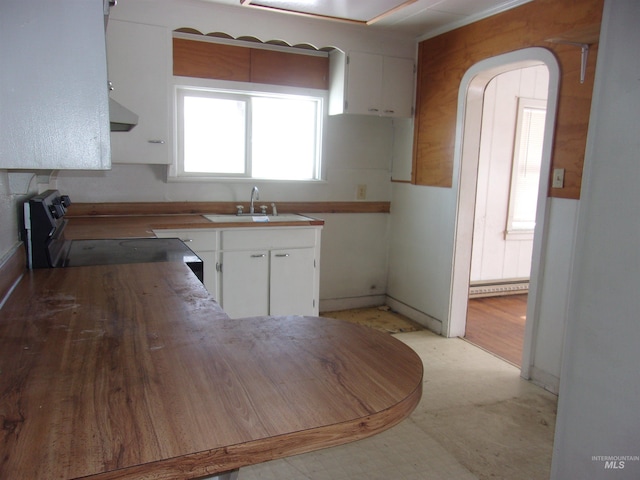 kitchen featuring electric range oven, a baseboard heating unit, white cabinets, a sink, and exhaust hood