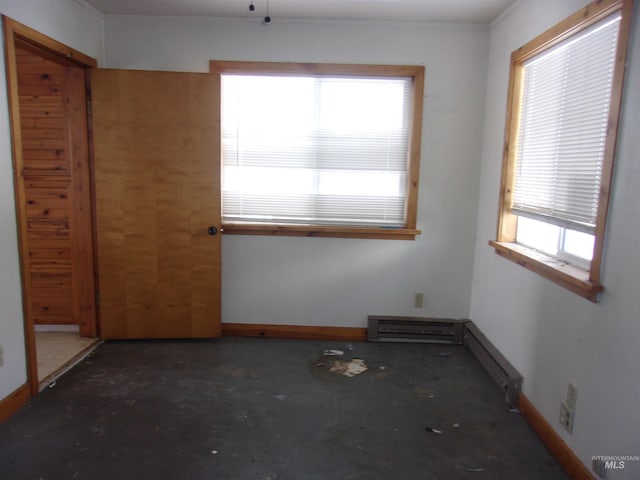 unfurnished room featuring concrete flooring, a baseboard radiator, and baseboards