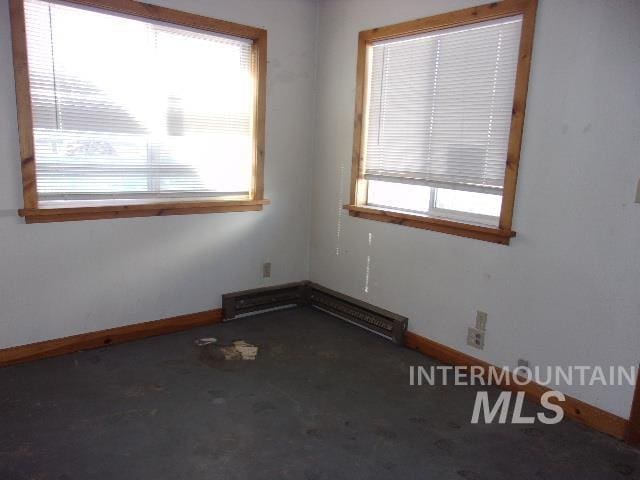 spare room with baseboard heating, plenty of natural light, and baseboards