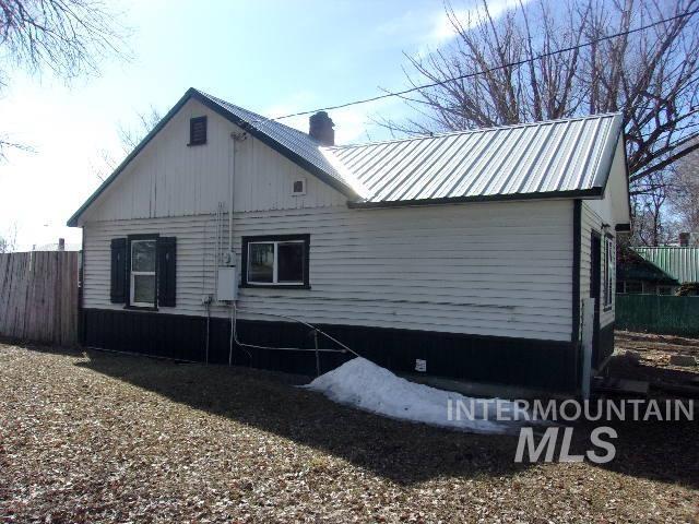 view of side of property with metal roof, a chimney, and fence