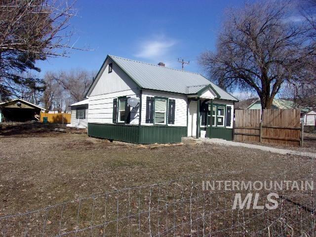 view of front of home featuring metal roof and fence