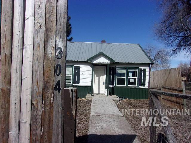 bungalow-style home featuring metal roof and fence