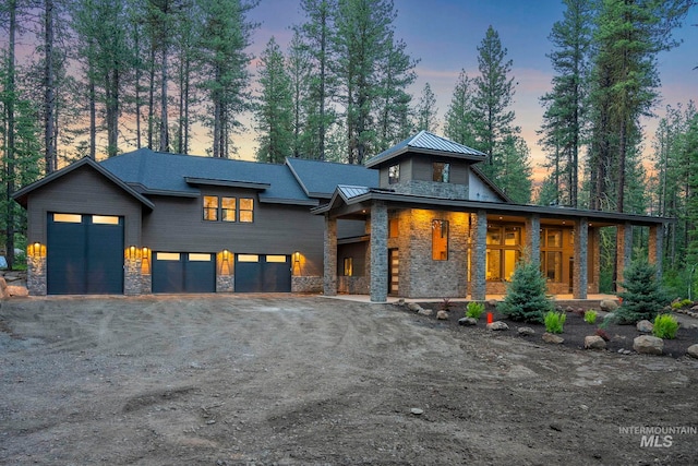 1010 Elo Rd, Mccall, ID 83638 - modern home with stone siding, a standing seam roof, covered porch, a metal roof, and driveway