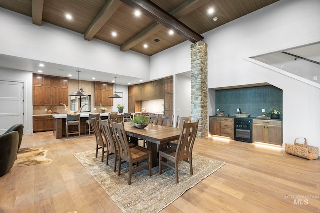 1010 Elo Rd, Mccall, ID 83638 - dining space featuring wine cooler, light wood-style flooring, a high ceiling, a wooden ceiling with exposed beams, and ornate columns