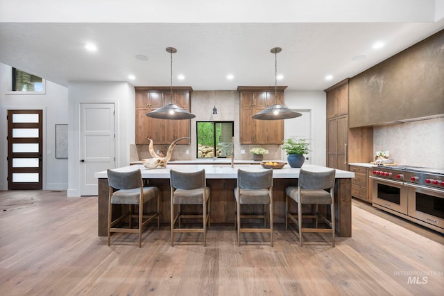 1010 Elo Rd, Mccall, ID 83638 - kitchen with double oven range, light countertops, decorative backsplash, light wood-style flooring, and a kitchen island with sink