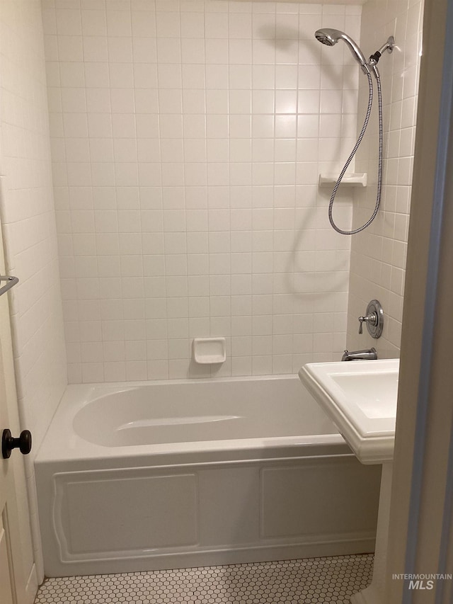 bathroom featuring tile patterned flooring, tiled shower / bath combo, and sink