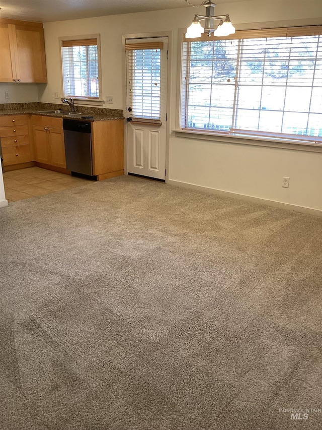 kitchen with light brown cabinetry, decorative light fixtures, sink, stainless steel dishwasher, and light colored carpet