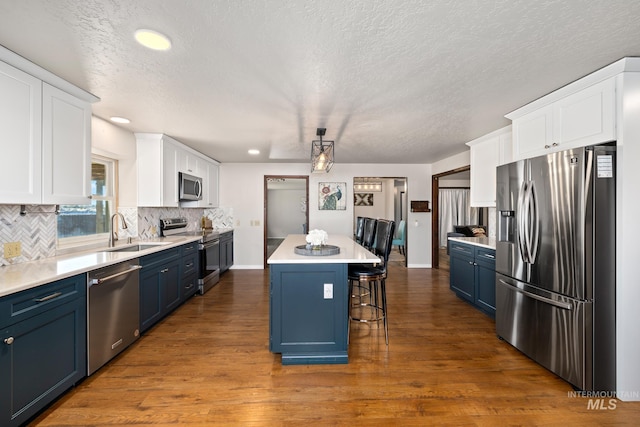 kitchen featuring blue cabinetry, white cabinets, a kitchen island, and stainless steel appliances