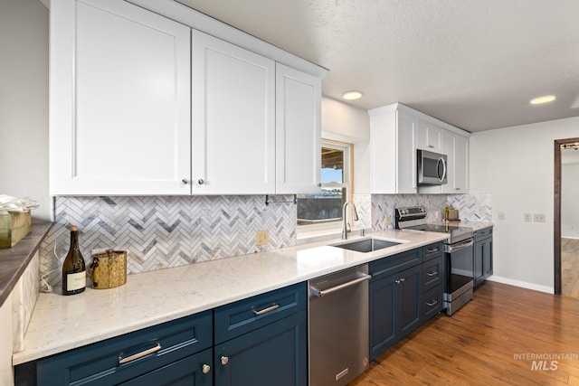 kitchen featuring white cabinets, blue cabinets, sink, dark hardwood / wood-style flooring, and stainless steel appliances