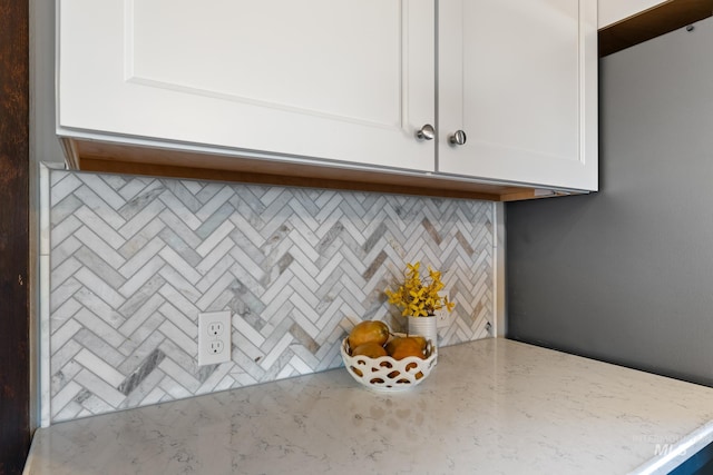 interior space featuring tasteful backsplash, light stone countertops, and white cabinets