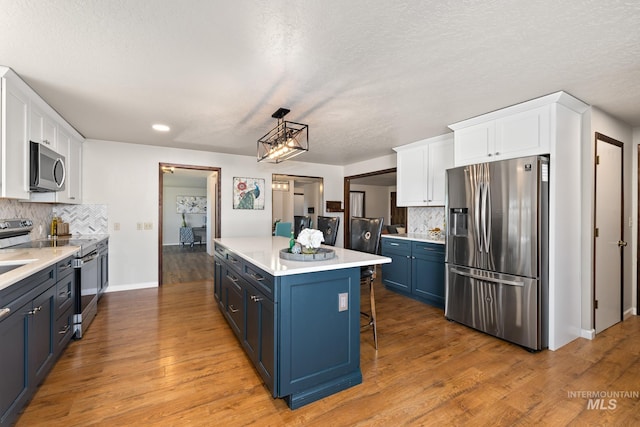 kitchen with white cabinetry, stainless steel appliances, hardwood / wood-style flooring, and blue cabinets