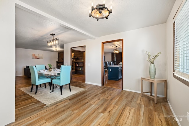 dining space featuring hardwood / wood-style flooring, a textured ceiling, and beamed ceiling