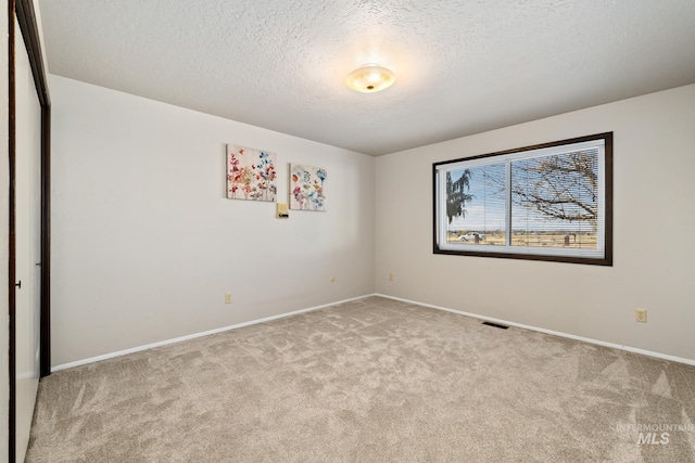 carpeted empty room with a textured ceiling