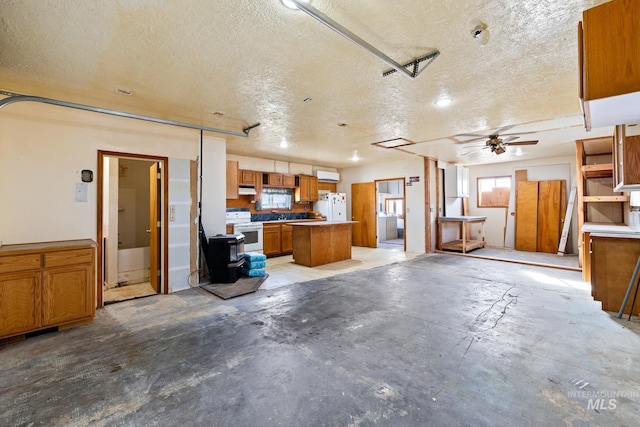 interior space with ceiling fan, a kitchen island, white appliances, and a textured ceiling