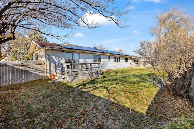 back of property with a lawn, solar panels, and a wooden deck