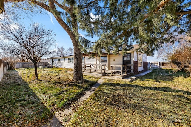 rear view of house featuring a wooden deck and a lawn