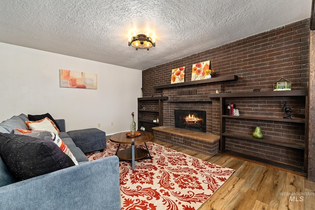 living room with a textured ceiling, light wood-type flooring, and a brick fireplace