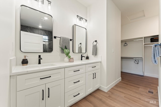 bathroom with double vanity, wood finished floors, a sink, and visible vents