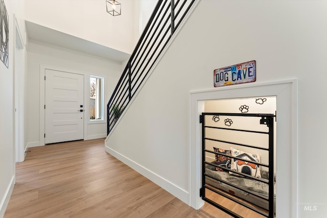 entrance foyer featuring light wood-style floors, baseboards, stairway, and a high ceiling