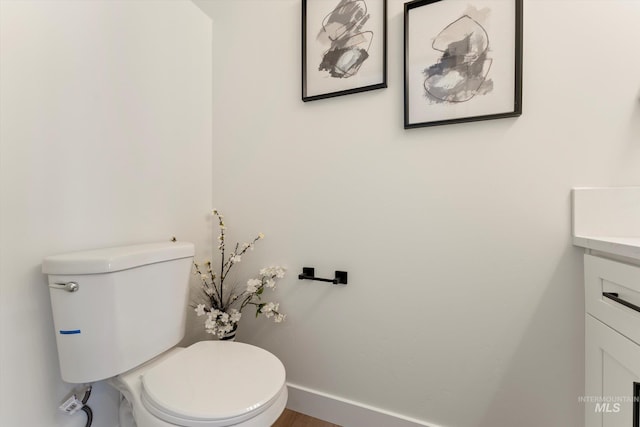 bathroom featuring toilet, baseboards, and vanity