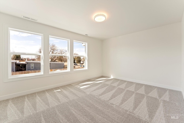 carpeted spare room featuring visible vents and baseboards