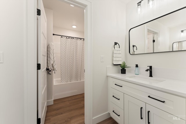 full bath with shower / tub combo, vanity, baseboards, and wood finished floors