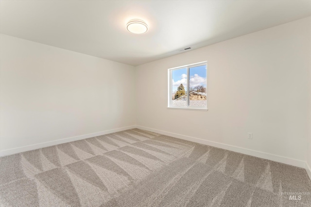 empty room featuring light carpet, visible vents, and baseboards