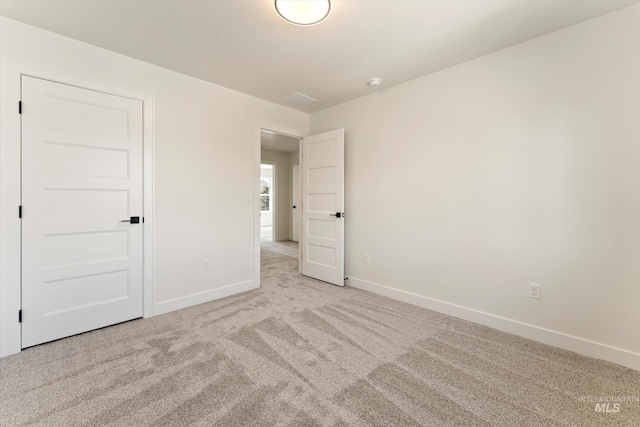 unfurnished bedroom featuring light carpet and baseboards