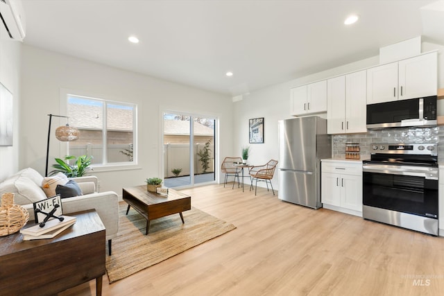 living room featuring light wood-style flooring, an AC wall unit, and recessed lighting