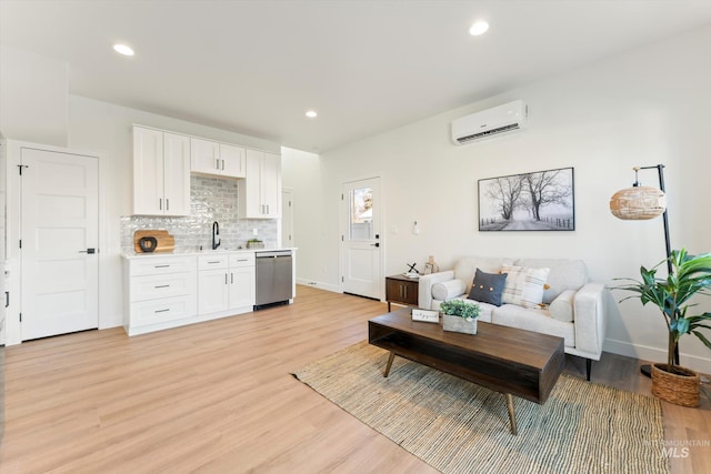 living room with baseboards, a wall unit AC, light wood-style flooring, and recessed lighting