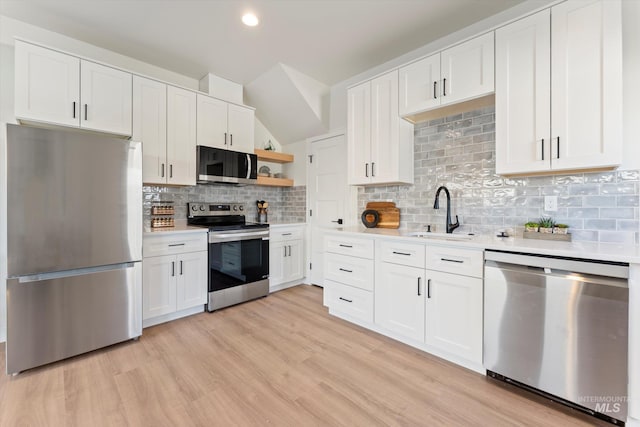 kitchen featuring stainless steel appliances, light countertops, a sink, and open shelves