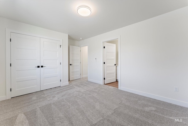 unfurnished bedroom featuring carpet floors, a closet, and baseboards