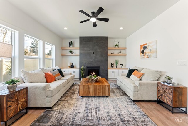 living area featuring a ceiling fan, a tiled fireplace, light wood-style flooring, and recessed lighting