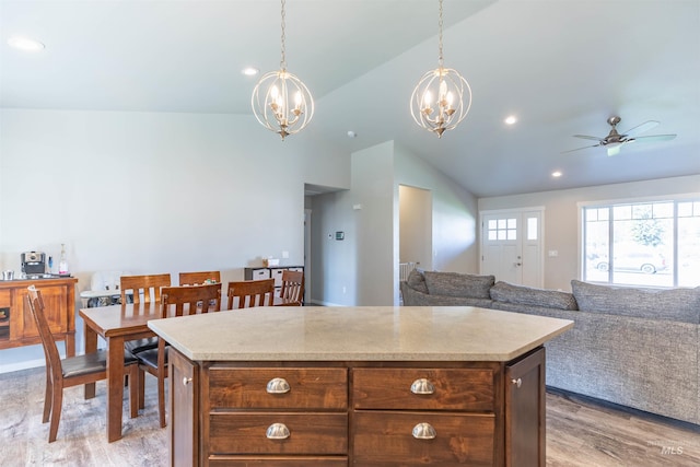 kitchen with a center island, light countertops, ceiling fan with notable chandelier, lofted ceiling, and light wood-style floors
