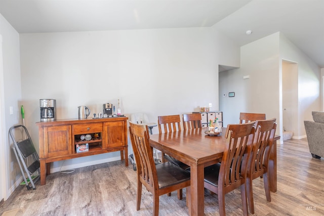dining space with vaulted ceiling and light wood-style flooring