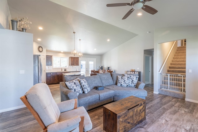 living area with stairway, ceiling fan, wood finished floors, and lofted ceiling