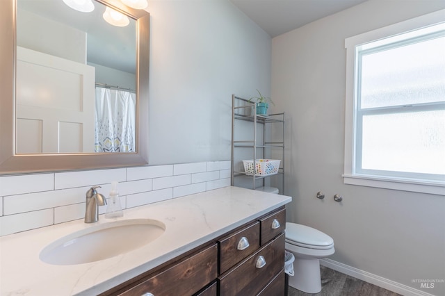 full bathroom featuring vanity, baseboards, plenty of natural light, and toilet