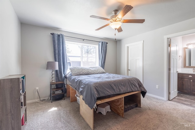 bedroom with baseboards, connected bathroom, and light carpet
