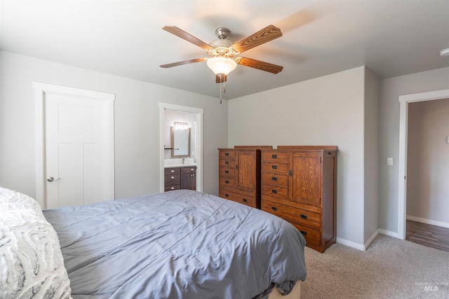 bedroom featuring baseboards, light carpet, a ceiling fan, and connected bathroom
