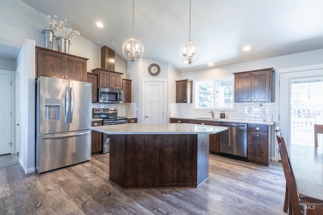 kitchen featuring an inviting chandelier, wood finished floors, a kitchen island, a sink, and stainless steel appliances