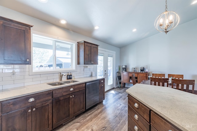 kitchen featuring backsplash, stainless steel dishwasher, a sink, a chandelier, and light wood-style floors