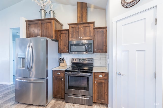 kitchen with tasteful backsplash, vaulted ceiling, baseboards, stainless steel appliances, and light wood-style flooring