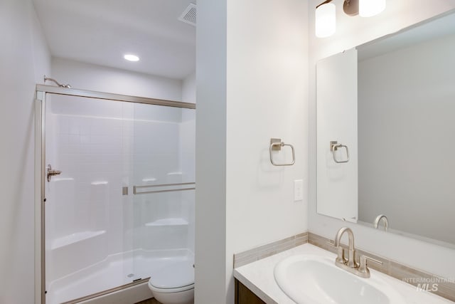 bathroom with vanity, toilet, and a shower with door